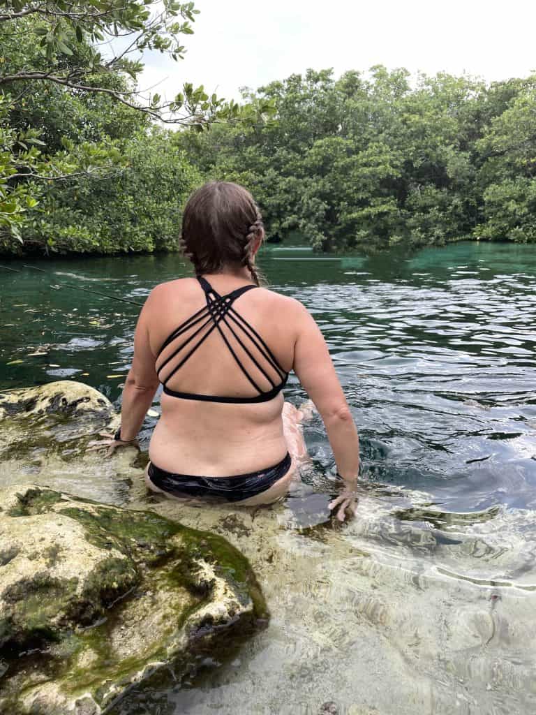 A girl with her back to the camera looking out at a cenote near Playa Del Carmen